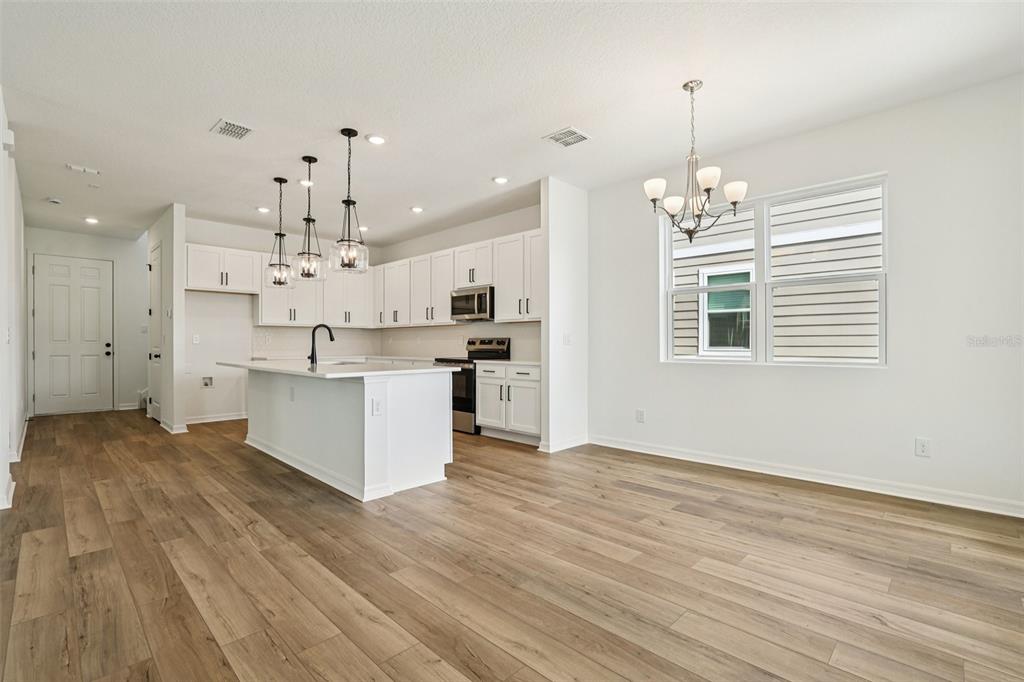 2491 Zuni Road St. Cloud, FL 34771 - Photo 7 of 42 a large kitchen with kitchen island a sink dishwasher a stove and white cabinets with wooden floor