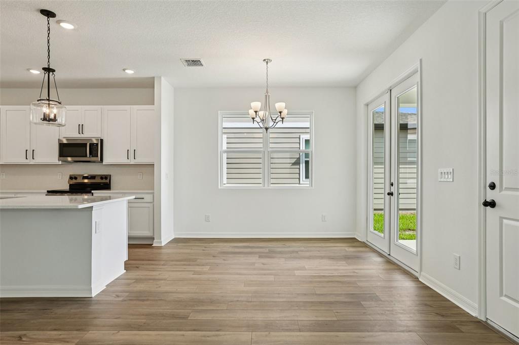 2491 Zuni Road St. Cloud, FL 34771 - Photo 8 of 42 a kitchen with kitchen island granite countertop a stove a refrigerator a sink and white cabinets with wooden floor