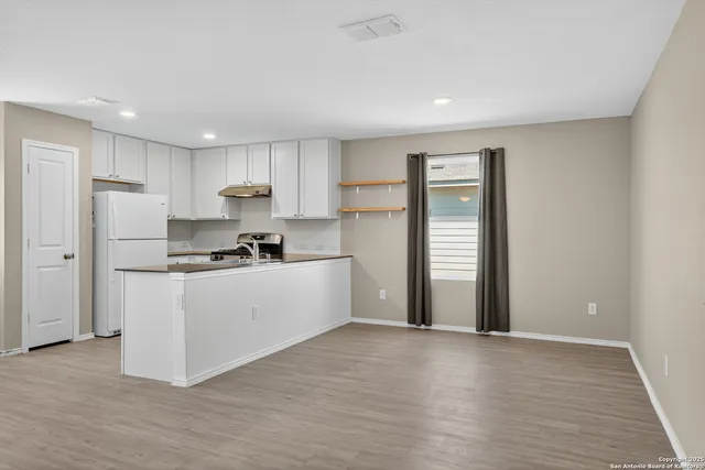 a kitchen with stainless steel appliances granite countertop a refrigerator sink and white cabinets
