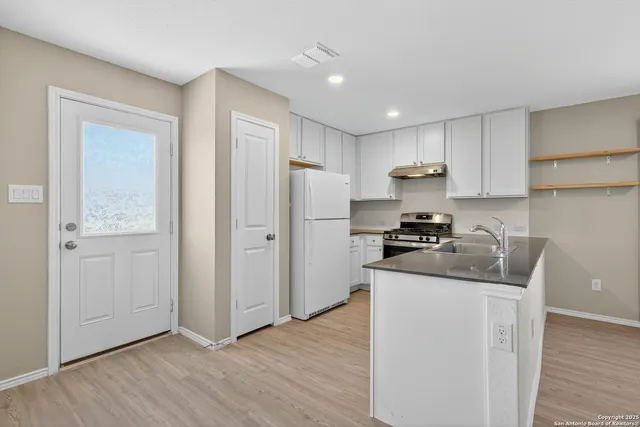 a kitchen with a refrigerator sink and cabinets