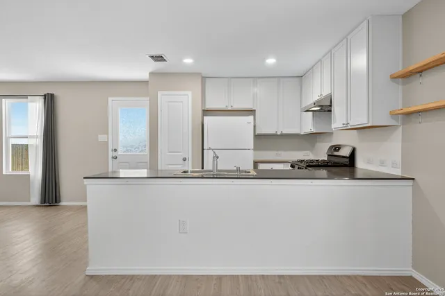 a kitchen with stainless steel appliances granite countertop a sink a stove and a refrigerator