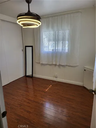 a view of empty room with wooden floor and chandelier