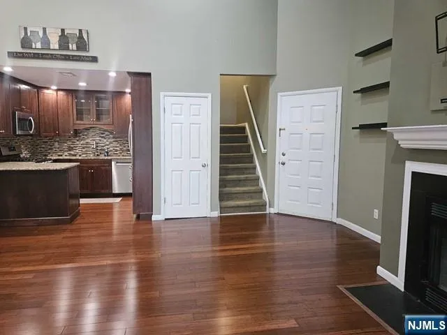 a view of a kitchen and an empty room with wooden floor