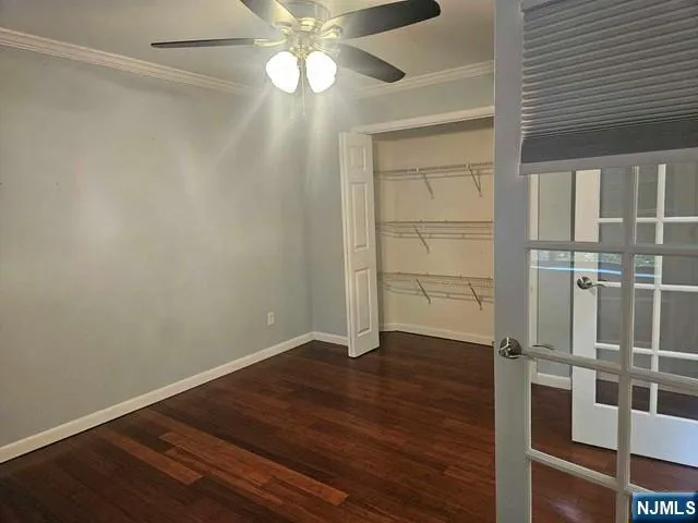 an empty room with wooden floor closet and windows