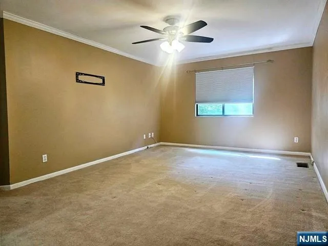 a view of an empty room with window and chandelier fan