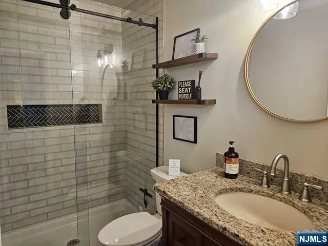 a bathroom with a granite countertop toilet sink and mirror