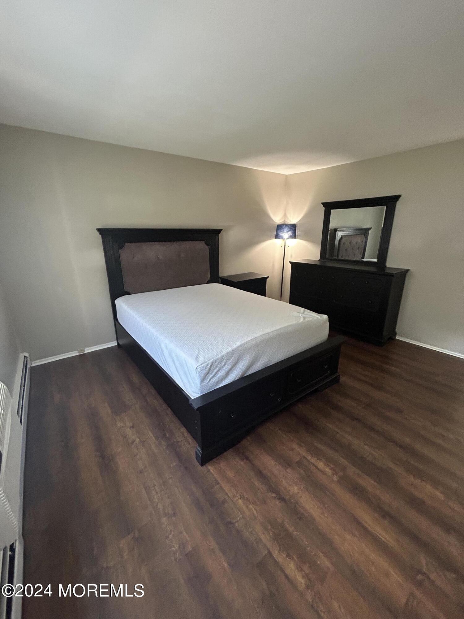 12 Manchester Court, Unit C Freehold, NJ 07728 - Photo 14 of 16 a spacious bedroom with a bed and wooden floor