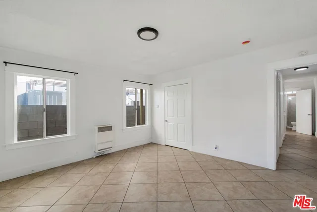 a view of an empty room with window and chandelier fan