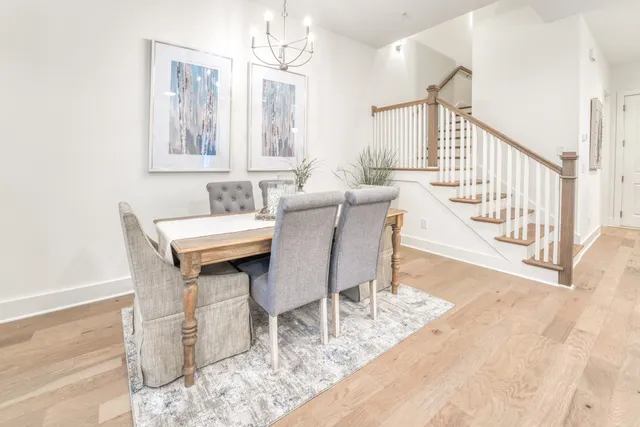 a dining room with wooden floor a chandelier a wooden table and chairs