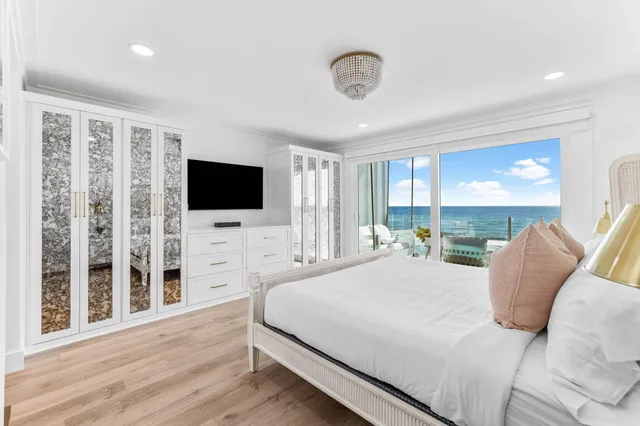 a bedroom with a flat screen tv a large window and a chandelier