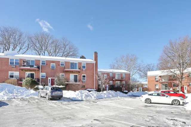 a front view of a building with cars parked