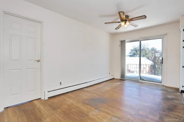 an empty room with wooden floor fan and windows