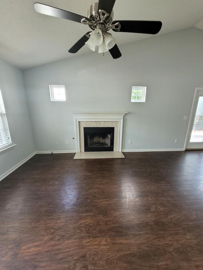 5517 Roan Place Raleigh, NC 27613 - Photo 3 of 35 an empty room with wooden floor chandelier fan and windows