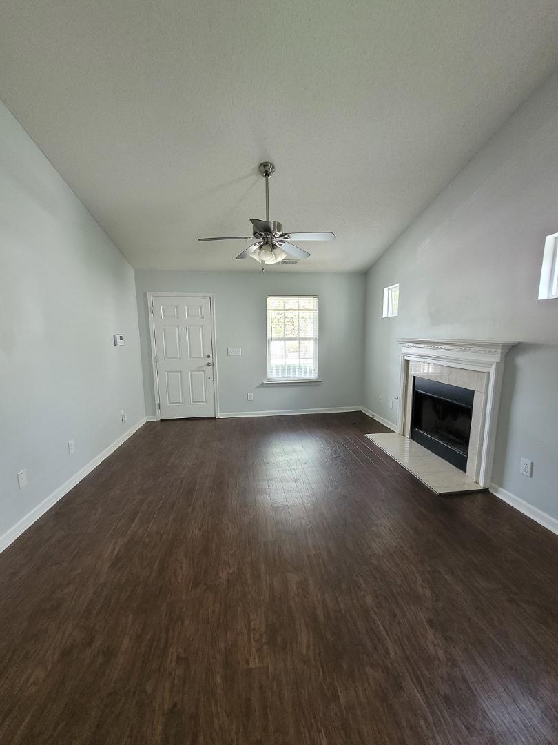 5517 Roan Place Raleigh, NC 27613 - Photo 5 of 35 an empty room with wooden floor fireplace and windows