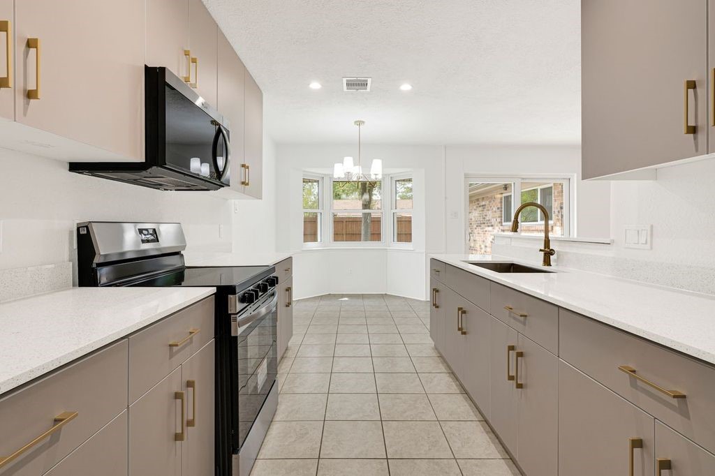 4518 Seneca Street Pasadena, TX 77504 - Photo 13 of 26 a kitchen with stainless steel appliances a sink dishwasher stove microwave and cabinets