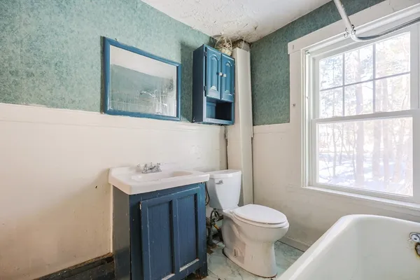 a bathroom with a toilet a sink a window and mirror