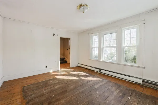 an empty room with wooden floor and windows