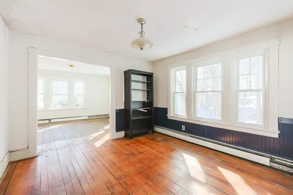 an empty room with wooden floor and windows