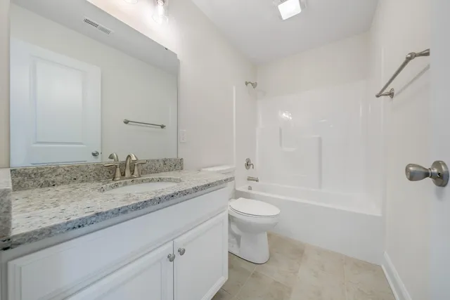 a bathroom with a granite countertop sink toilet a mirror and bathtub