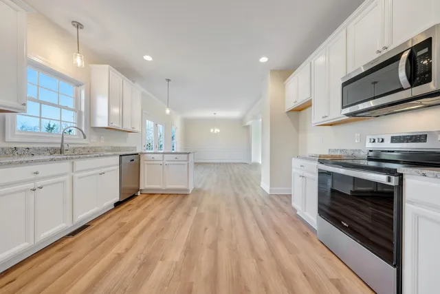 a kitchen with stainless steel appliances granite countertop a stove a sink and a microwave