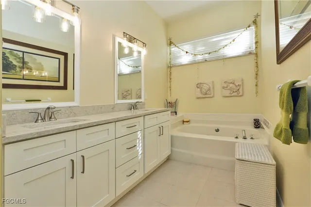 a bathroom with a granite countertop sink a large mirror a bathtub and next to a window
