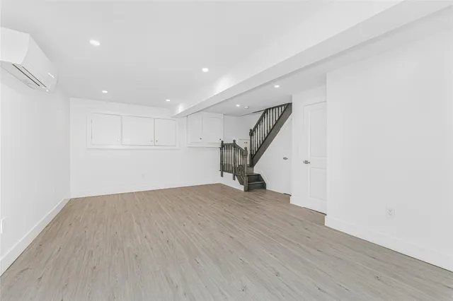 a view of an empty room with wooden floor and stairs
