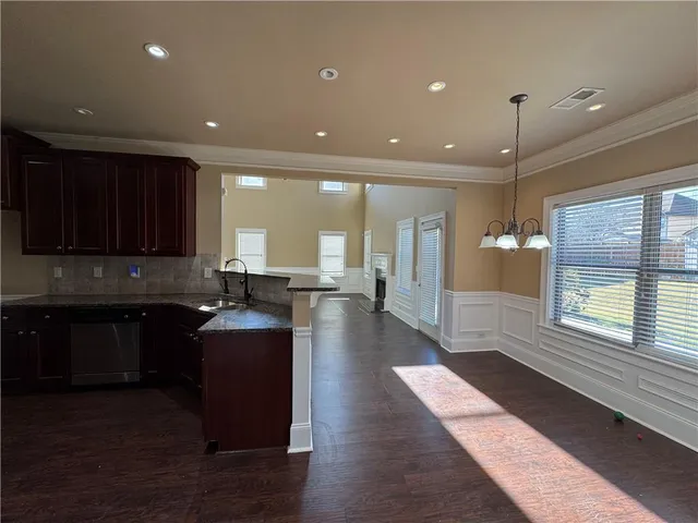 a large kitchen with stainless steel appliances granite countertop a stove a sink a refrigerator white cabinets and wooden floor