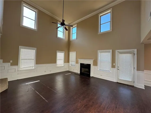 an empty room with wooden floor fireplace and windows
