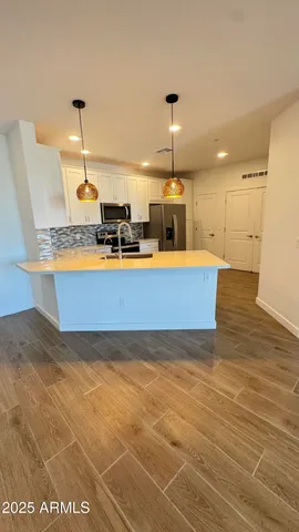 a view of a kitchen with kitchen island stainless steel appliances a sink cabinets and wooden floor