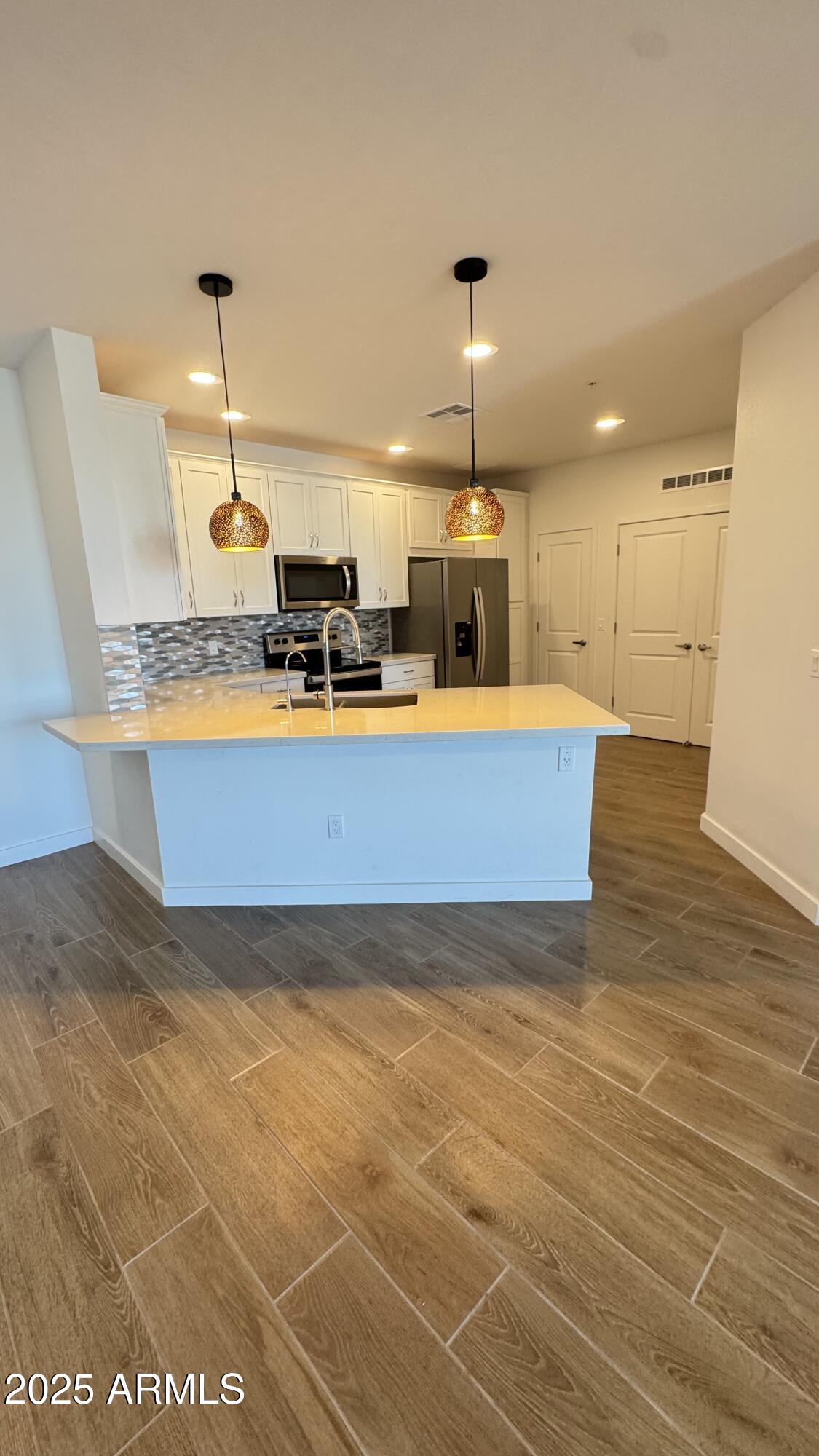 2511 West Queen Creek Road, Unit 377 Chandler, AZ 85248 - Photo 6 of 47 a view of a kitchen with kitchen island stainless steel appliances a sink cabinets and wooden floor