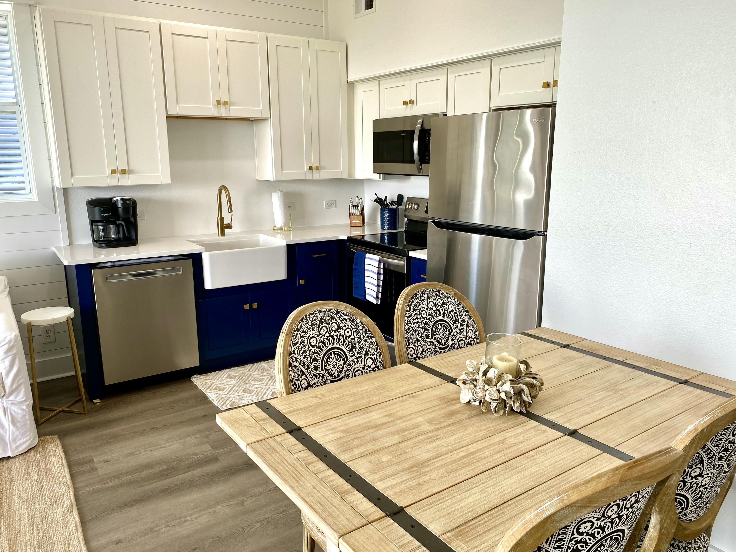 145 Spires Lane, Unit 411 Santa Rosa Beach, FL 32459 - Photo 16 of 44 a kitchen with stainless steel appliances kitchen island granite countertop a refrigerator a stove a sink dishwasher with a dining table and chairs