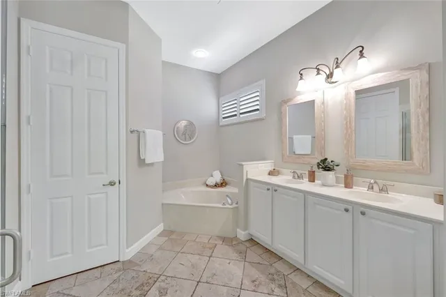a bathroom with a double vanity sink mirror and bathtub