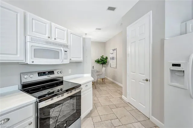 a kitchen with white cabinets and appliances