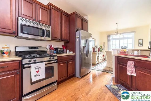 a kitchen with stainless steel appliances granite countertop a stove a sink dishwasher a refrigerator and a microwave oven with large wooden cabinets