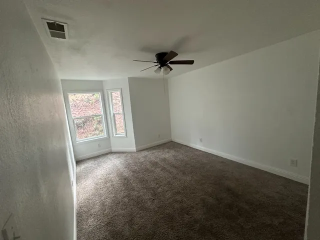 an empty room with windows and fan