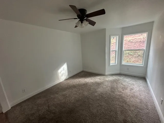 en empty room with windows and fan