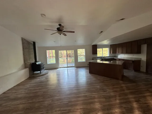 a view of an empty room with a kitchen and a window
