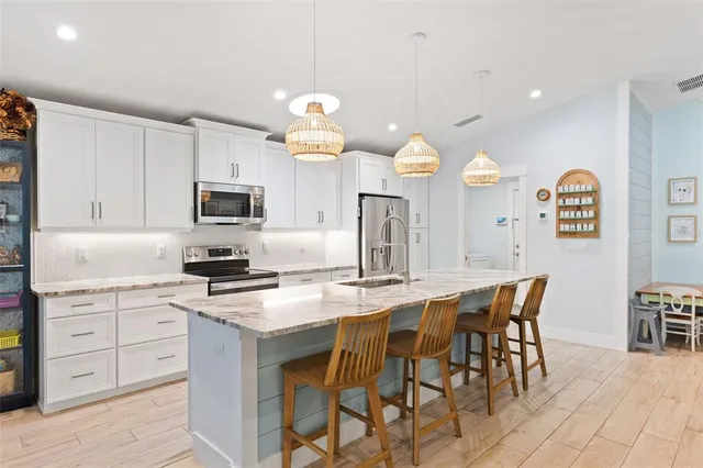 a kitchen with stainless steel appliances granite countertop a refrigerator a microwave a stove and white cabinets