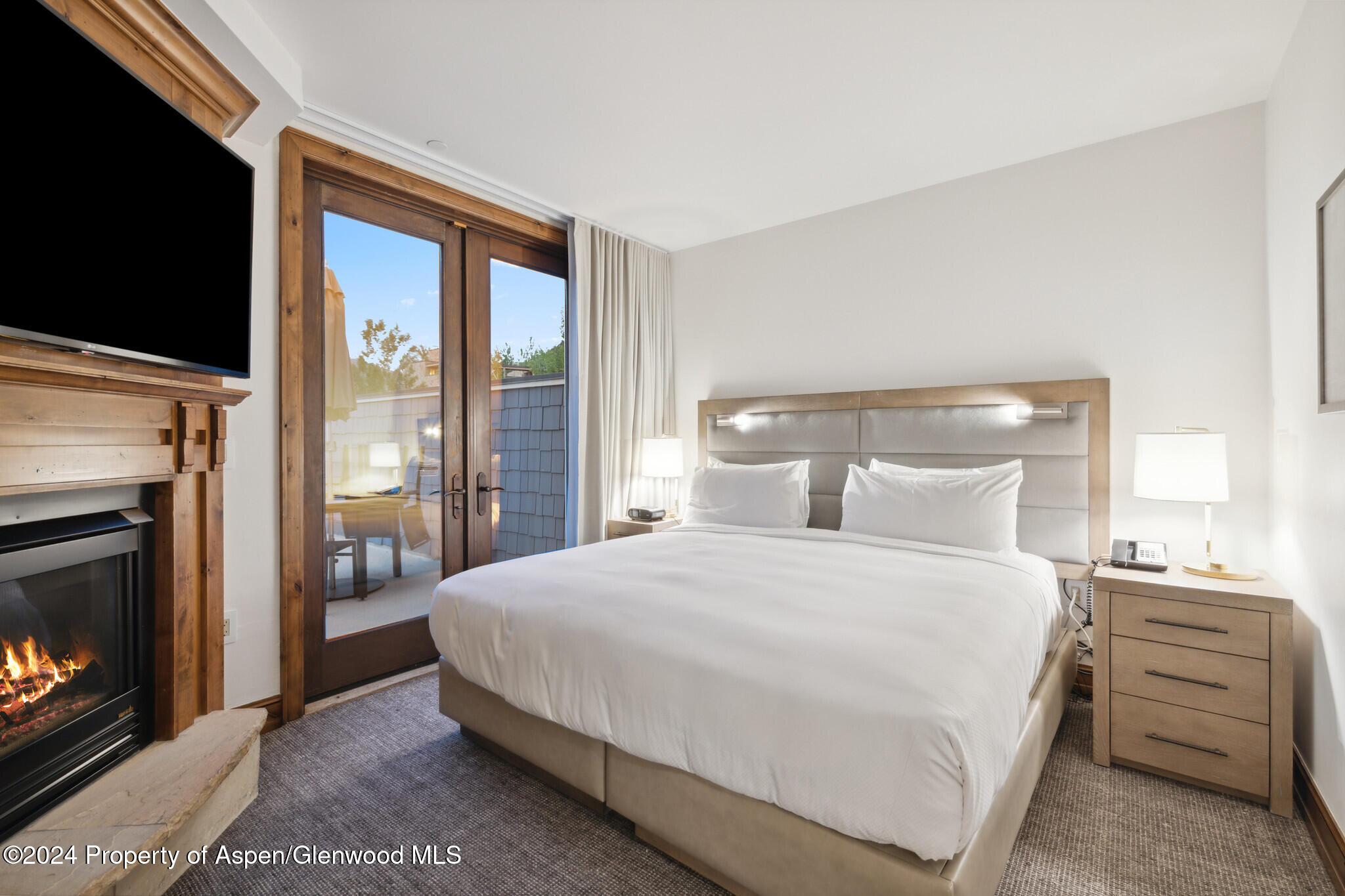 415 East Dean St Unit 46 Week 12 Aspen, CO 81611 - Photo 17 of 27 a bedroom with a bed a fireplace and a flat tv screen