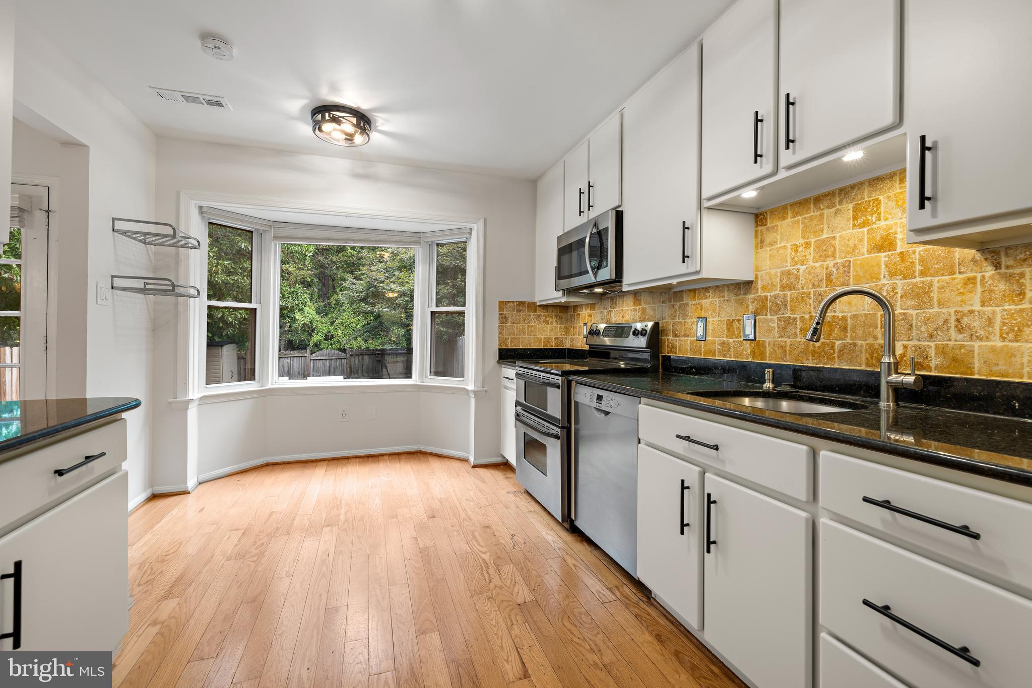 a kitchen with granite countertop a sink cabinets stainless steel appliances and a window