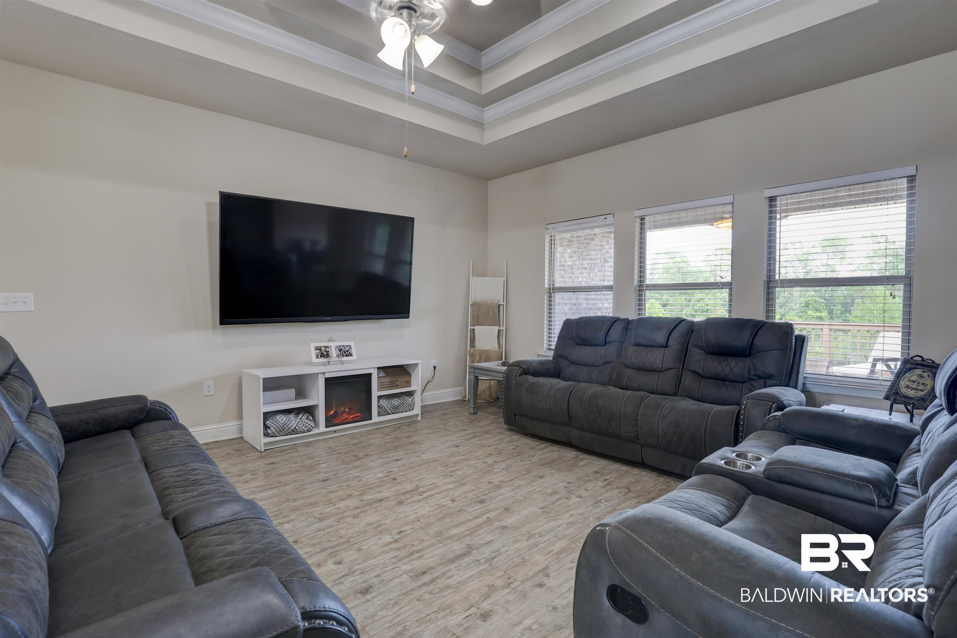 21902 Yosemite Boulevard Fairhope, AL 36532 - Photo 7 of 32 Living room featuring a raised ceiling, light hardwood / wood-style flooring, a fireplace, crown molding, and ceiling fan