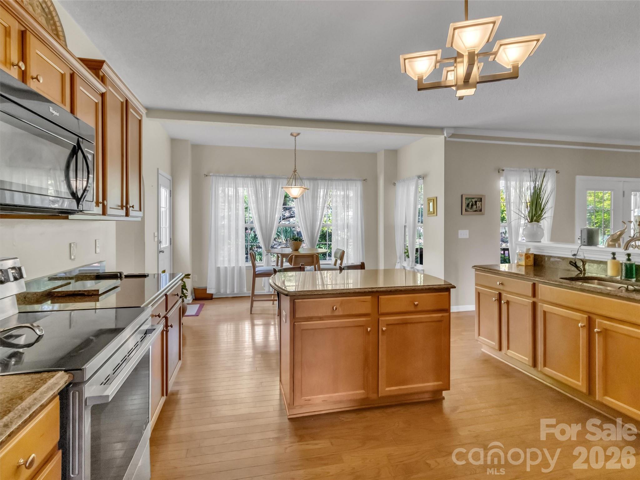 237 Midway Crossing Drive Clyde, NC 28721 - Photo 16 of 42 a large kitchen with stainless steel appliances a stove a sink dishwasher a dining table and chair with wooden floor