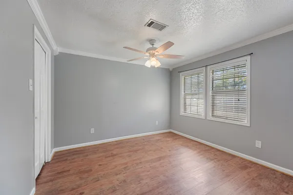 a view of an empty room with a window and wooden floor