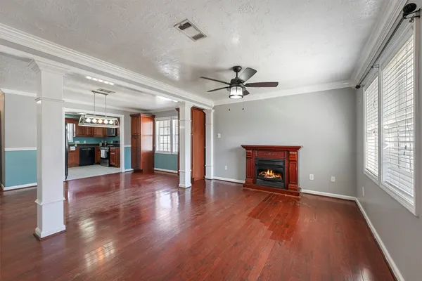 a view of an empty room with wooden floor fireplace and a window
