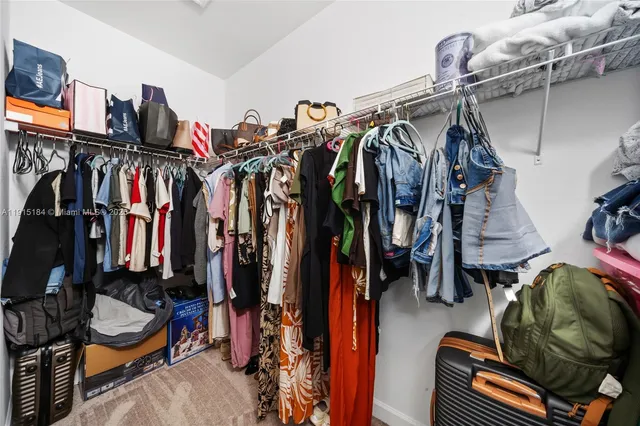 a view of walk in closet with clothes and shoes