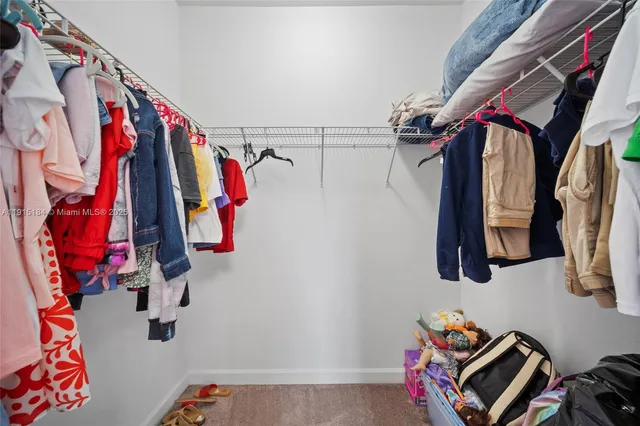 a view of walk in closet with clothes and shoes