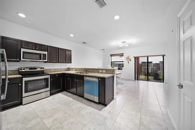a large kitchen with a large counter top stainless steel appliances and cabinets