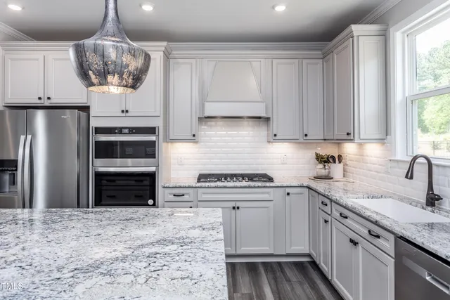 a kitchen with stainless steel appliances granite countertop stove a sink a center island and windows