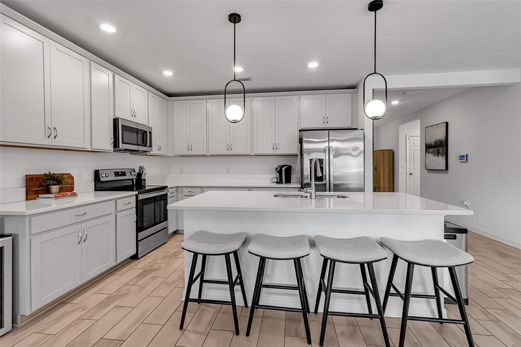 5434 Patano Loop Palmetto, FL 34221 - Photo 13 of 93 a kitchen with stainless steel appliances granite countertop a sink a microwave oven a refrigerator with white cabinets and wooden floor
