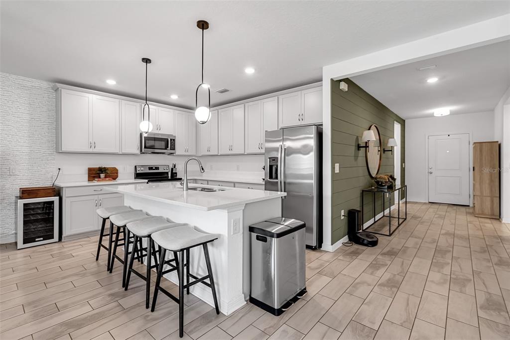 5434 Patano Loop Palmetto, FL 34221 - Photo 10 of 93 a kitchen with kitchen island a refrigerator a stove a oven a sink a dining table and chairs with wooden floor